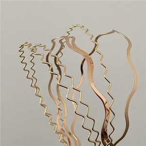 Macro detail of various golden wavy metal headbands with textured wave patterns