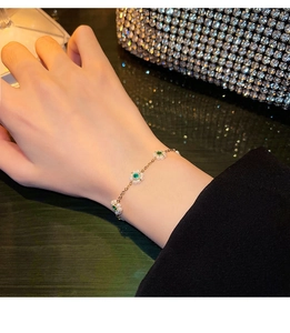 Close-up of vintage gold floral bracelet featuring emerald green gems and tiny white pearls