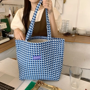 Detail of blue and white plaid woolen tote bag with decorative purple patch and wide strap