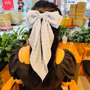 Detail of light blue oversized bow hair clip with wavy ribbons and 3D dot texture