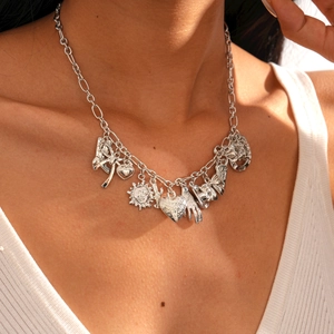 Close-up of metallic sweater necklace with sun, heart, and boot charms on a model