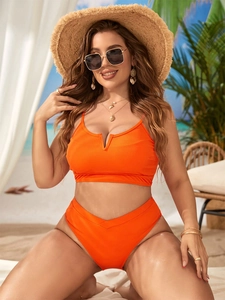 Detail eines leuchtend orangefarbenen High-Waist-Bikini-Sets mit geripptem Stoff am Strand