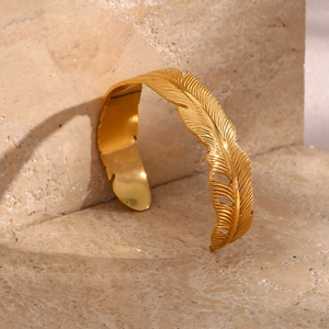 Macro shot of 18K gold plated leaf feather open bangle with detailed embossed textures
