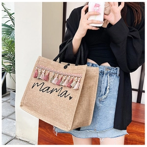 Close-up of large jute tote bag featuring mama print and colorful fringe tassels decoration