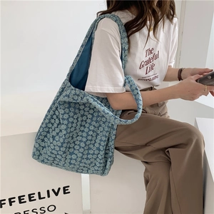 Detail of blue floral lace tote bag showing textured jacquard fabric and wide shoulder strap