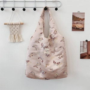 Detail of pink jacquard butterfly shoulder bag with retro woven label on white wall
