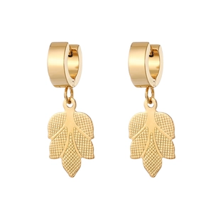 Close-up of golden leaf pendant earrings showing intricate vein textures and polished huggie
