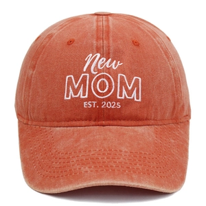 Detailopname van het witte New Mom borduursel op een gewassen oranje katoenen honkbalpet