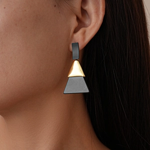 Gros plan de boucles d'oreilles géométriques en acrylique avec triangle doré et trapèze