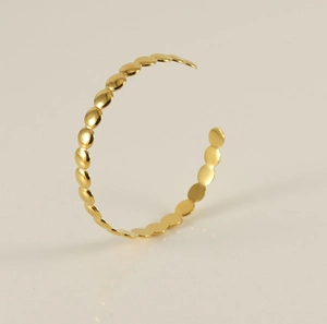 Macro detail of minimalist 18K gold plated stainless steel twisted beaded open bangle