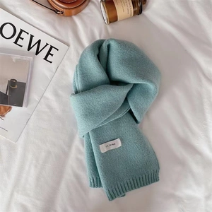 Detailed texture of light blue knitted scarf with Feiding brand tag on white sheet
