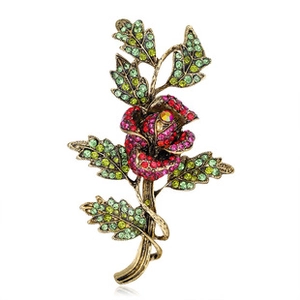 Dettaglio della spilla a rosa in bronzo vintage con strass rossi e verdi lucidi