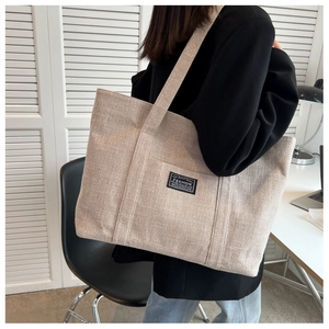 Close-up of the thick textured canvas tote bag with fashion label and shoulder strap
