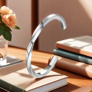 Detailed view of silver twisted mobius bangle on desk with notebooks and flowers