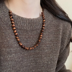 Close-up of vintage beaded necklace with tiger eye stones on a knit sweater