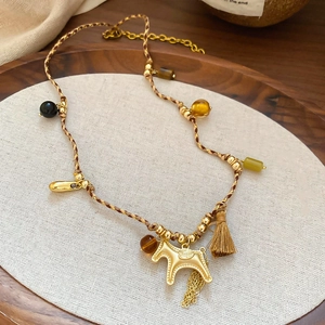 Detailed view of woven rope necklace with golden pony pendant and vintage tassel