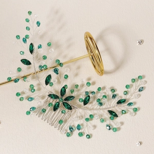Detail of vintage gold bridal hair comb with green emerald crystals on textured beige paper
