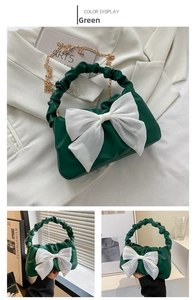 Detail of green ruched handbag featuring a large white bow and gold chain strap