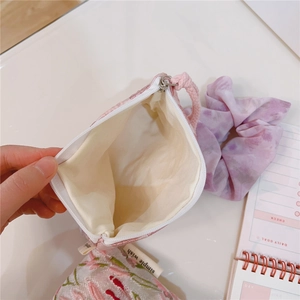 Detail view of pink floral embroidered pouch with beige fabric lining and zipper closure