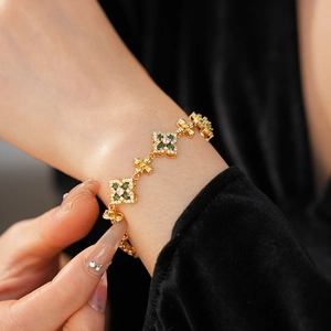 Detalle de pulsera vintage dorada con flores de circón sobre terciopelo negro