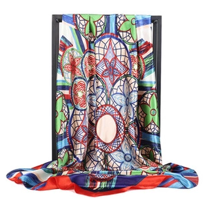 Detailed view of colorful geometric floral patterns on long silk scarf hanging on frame