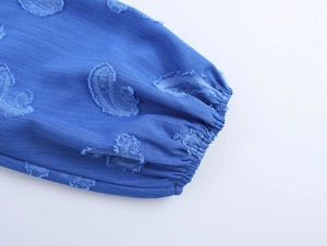 Détail du poignet d'une robe bleue avec broderie de cœur et fermeture élastiquée