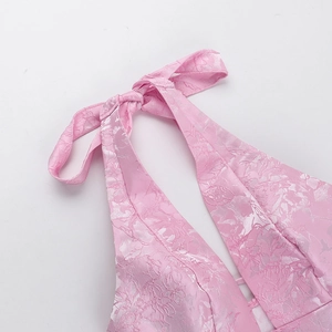 Detailed close-up of pink halter neckline with floral jacquard texture and bow tie