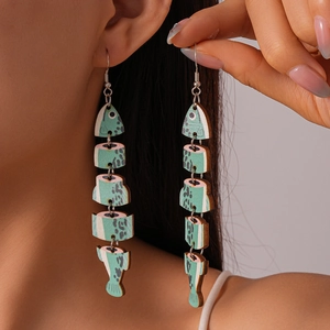 Close-up of fish-shaped wooden drop earrings with green and pink floral patterns