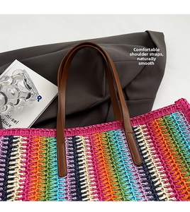 Detail of multi-colored woven straw tote bag with brown leather strap and stitching