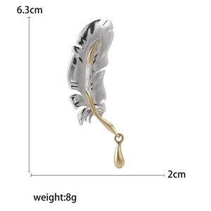 Fashionable feather-shaped brooch in silver and gold tones with a gold teardrop pendant