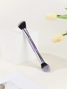 Detail showing dual-ended purple makeup brush with black and white bristles and logo