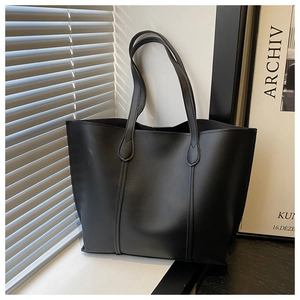 Detailed view of black tote bag with matte leather texture and stitching accents