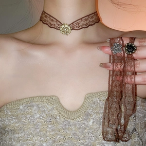 Detail of vintage brown lace choker with gold star and silver flower pendants