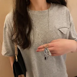Macro view of crystal encrusted feather pendant on long chain necklace for women