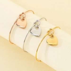 Detailed view of three stainless steel heart pendant bracelets in gold, silver, and rose gold