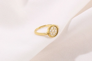 Macro shot of gold hexagon ring with clear zircons on premium white satin fabric