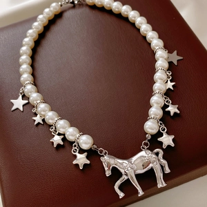 Detail of pearl necklace featuring silver horse pendant and stars on leather jewelry box