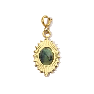Macro shot of gold pendant with green stone and radial sunburst texture details