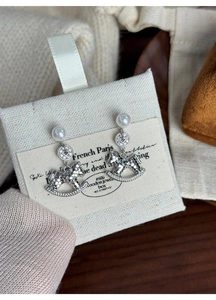 Detail of silver rocking horse stud earrings with sparkling crystals and a pearl accent