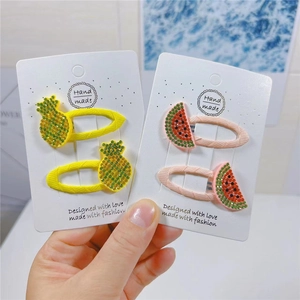 Close-up of handmade fruit hair clips with rhinestones in pineapple and watermelon shapes