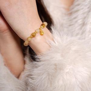 Détail macro du bracelet en perles de citrine avec pendentif poisson doré au poignet