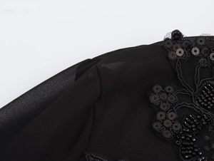 Close-up of elegant black chiffon shirt with beaded lapel and intricate lace embroidery