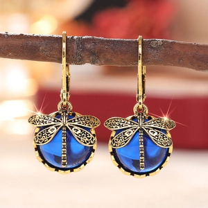 Vintage goldene Libellenohrringe mit dunkelblauen Edelsteintropfen an einem Holzzweig