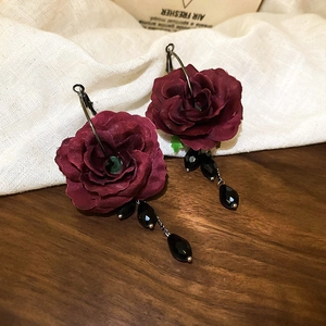 Detailed shot of vintage deep red fabric rose earrings with black crystal beaded tassels