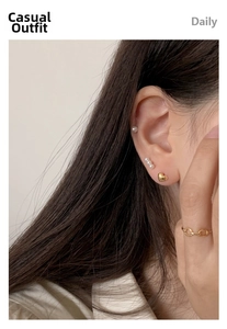 Detail of 18K gold-plated heart stud earrings and pearl accents worn by a model