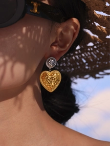 Detailed shot of two-tone heart drop earrings with hammered texture on female model