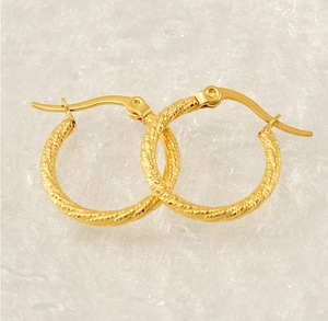 Detailed macro view of gold-plated twisted hoop earrings with a spiral texture finish