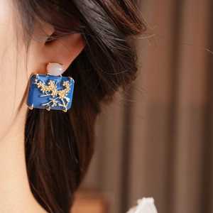 Close-up of vintage enamel geometric earrings with gold flower pattern on model's ear