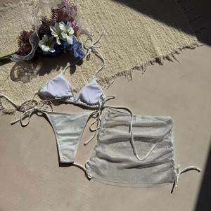 Vue détaillée d'un ensemble bikini blanc trois pièces avec une jupe paréo en maille