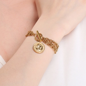 Close-up of gold layered chain bracelet with portrait coin pendant and OT toggle clasp